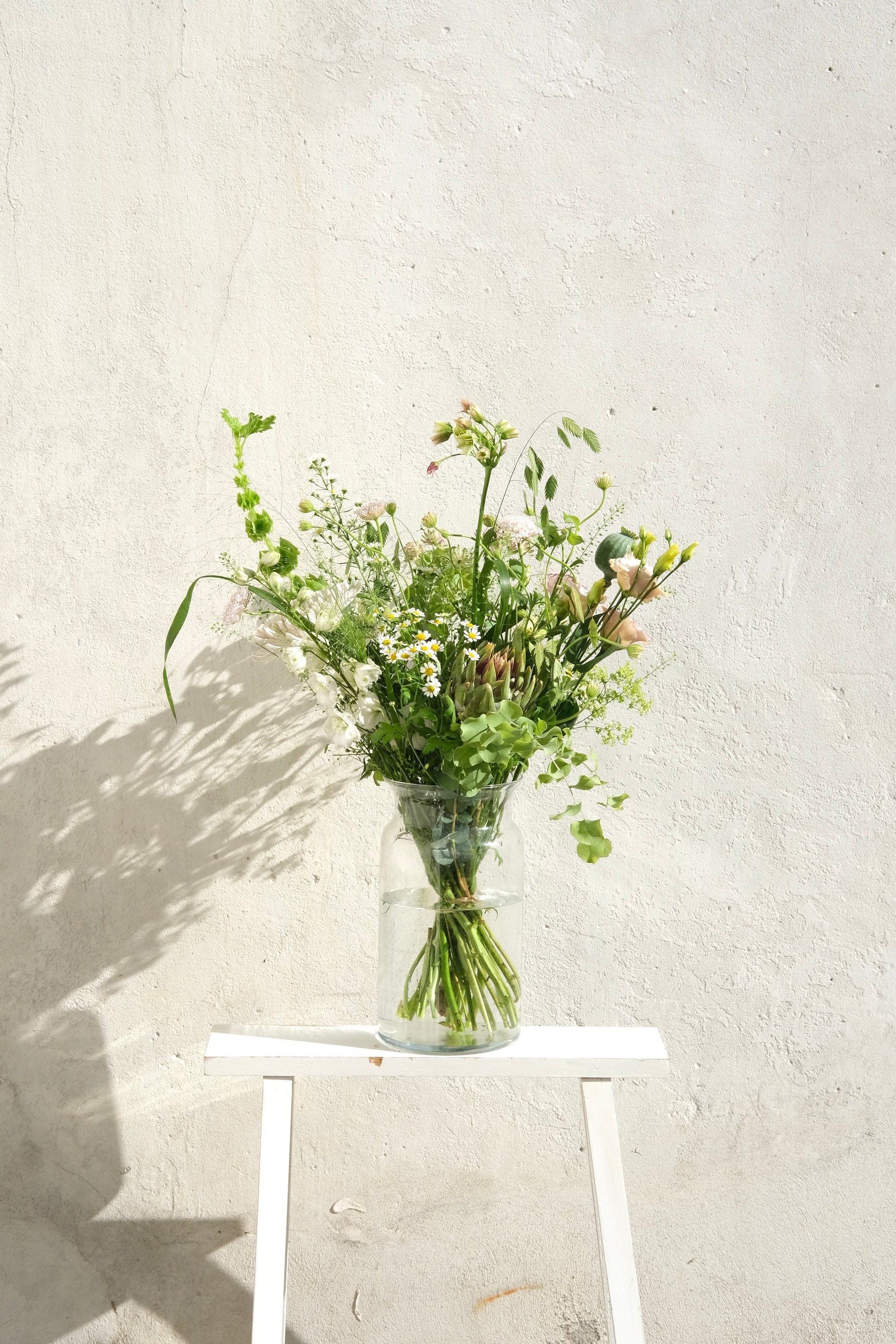 Håndbundet mellem buket med vilde blomster og grønne detaljer